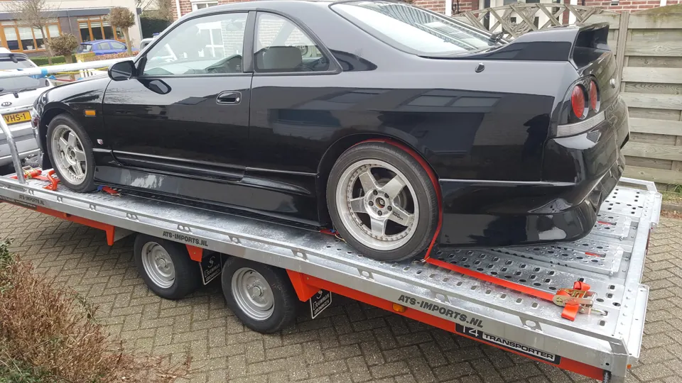 Zwarte Nissan Skyline R33, zijaanzicht op trailer