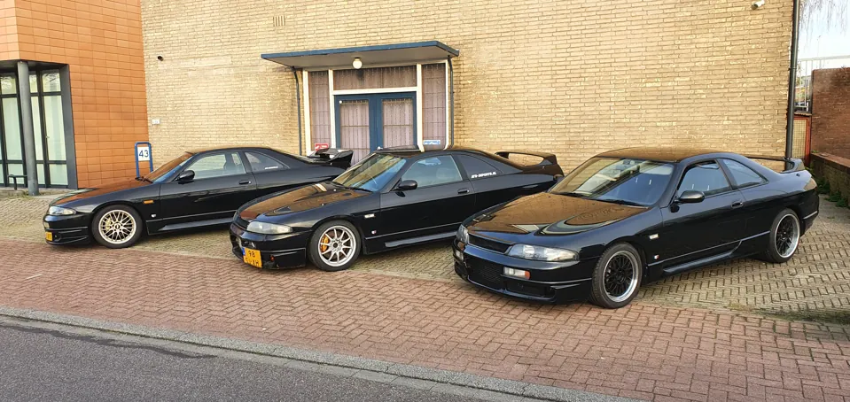 Drie zwarte Nissan Skyline R33 coupés voor het pand