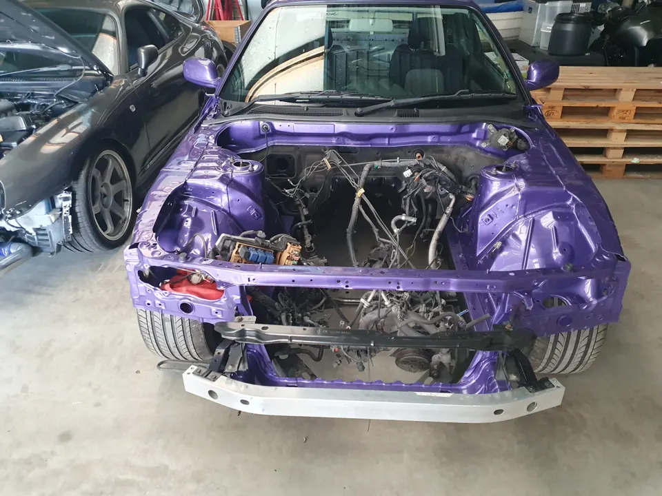 Paarse projectauto met lege motorruimte en gedemonteerde neus