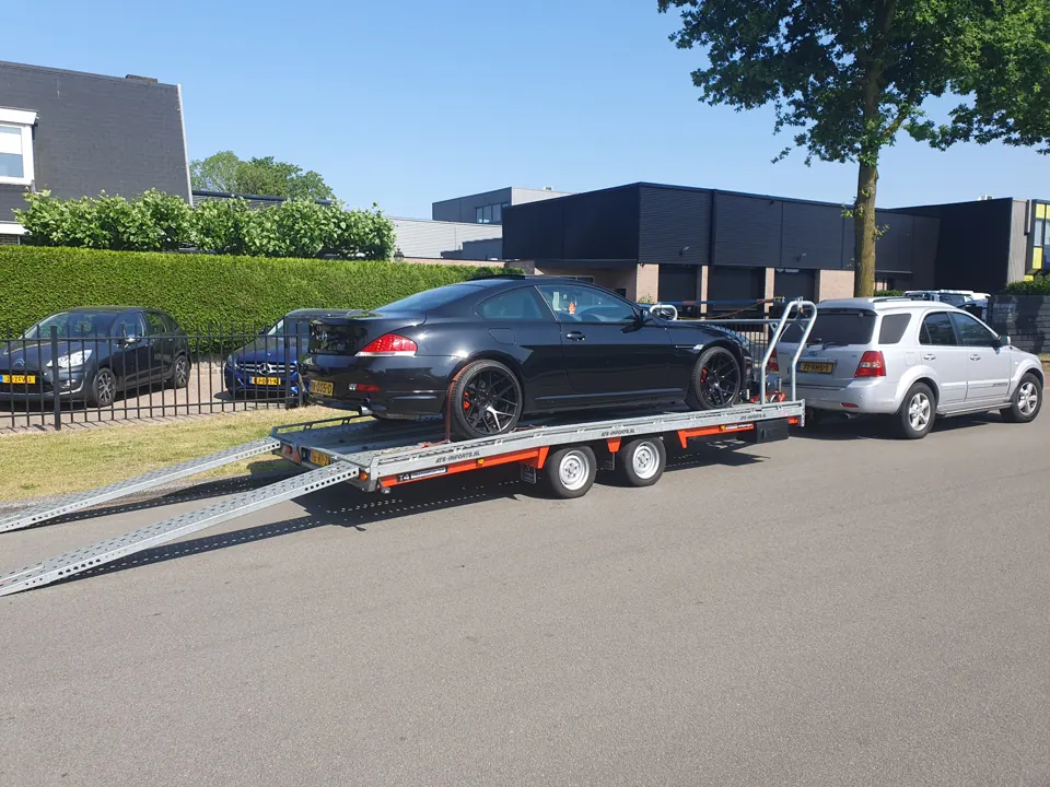 Auto en trekauto met lange lage trailer in zijaanzicht