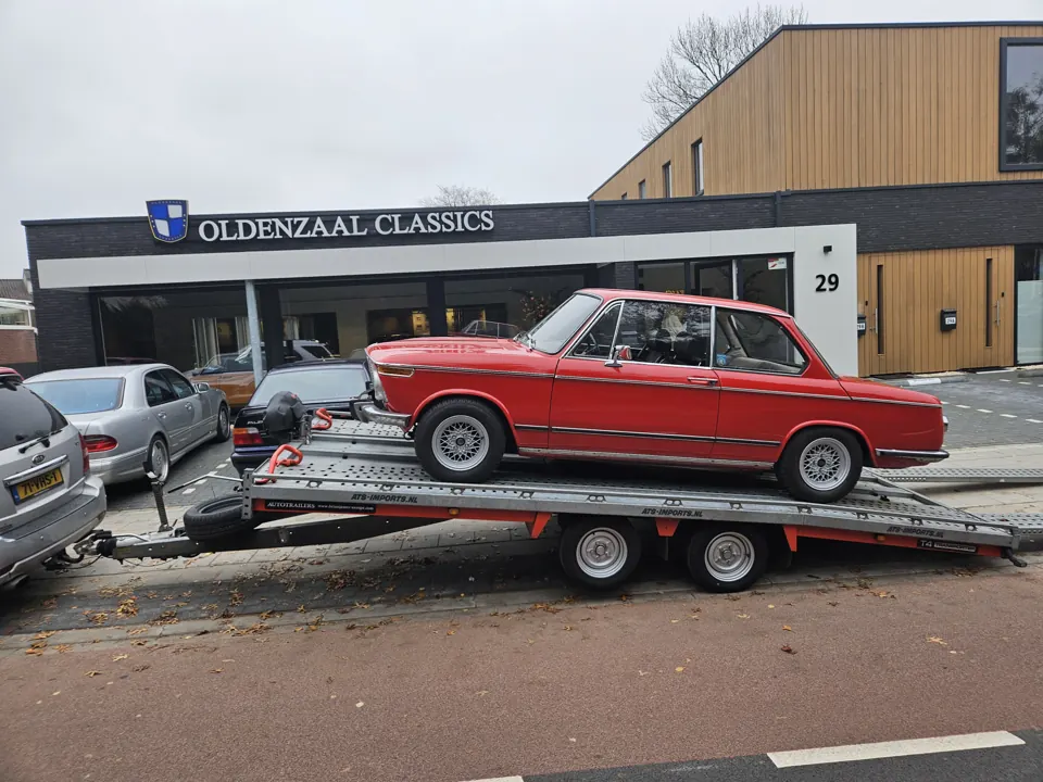 Rode klassieke BMW op trailer bij bedrijfspand