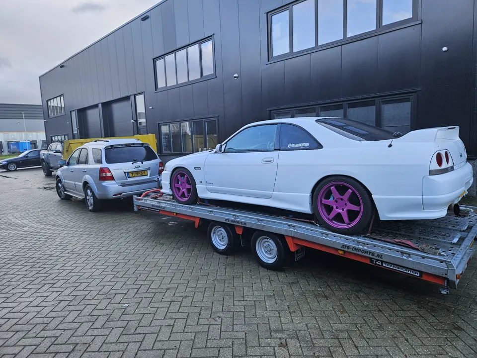 Witte Nissan Skyline R33 met paarse wielen op trailer